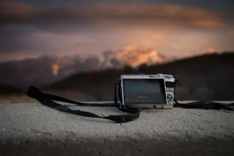 Small pockect size digital camera photographing sunset over mountains Stock Photos