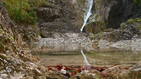 A small pond from a mountain stream in front of a waterfall in autumn Video stock 260862698