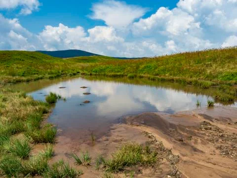 Small pond on the mountain top with clouds reflecting on water. Photos