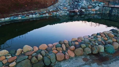 A small pond with rocks and a bench Stock Footage 273010624