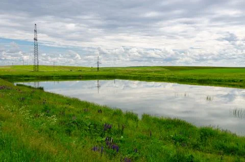 Small pond surrounded by green fields, rural landscape Stock Photos