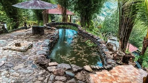 A small pool with a stone wall and a stone path Stock Photos
