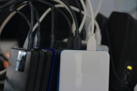 Small portable hard drives in stack connected to rear PC backup digital compu Stock Photos