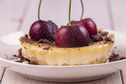 Small portion chessecake decorated with sweet cherries over on white wooden b Stock Photos