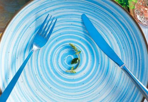 A small portion of a small lettuce leaf on a white plate with a knife and fork Stock Photos