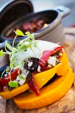 Small pot of stew and a stack of fresh vegetables and a sour cream garnish 스톡 사진