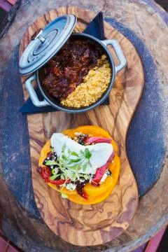 Small pot of stew and a stack of fresh vegetables and a sour cream garnish Foto stock