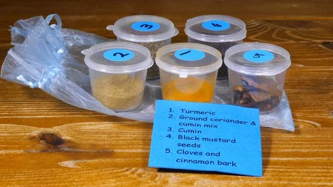 Small pots of Indian spices and an identifying list. Video stock 129197319