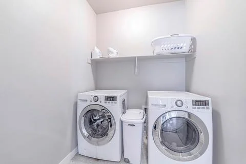 Small practical laundry room of house with washing machine and dryer appliances Stock Photos