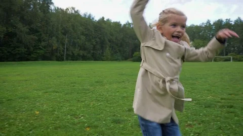 Small preschooler smiling caucasian girl in jacket is running and laughing Stock Footage