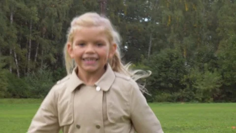 Small preschooler smiling caucasian girl in jacket and blue jeans is running Stock Footage