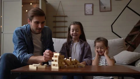 Small pretty girls plays a tiny jenga with father, all have great time together. Stock Footage 197377352