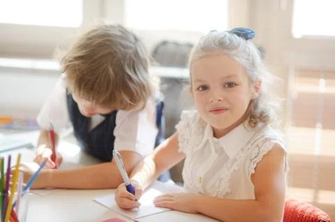 Small primary school students, boy and girl, performing a task. Stock Photos
