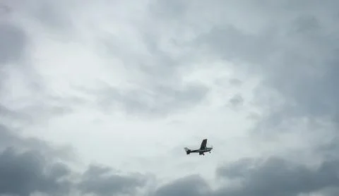 Small private plane flying in cloudy sky. White crop duster flight Stock Photos