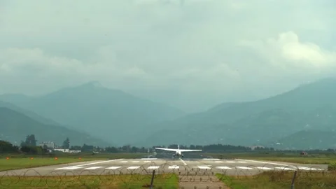 Small private white plane lands at airport against backdrop of large mountains Vidéo 213939249