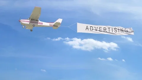 Small propeller airplane towing banner with ADVERTISING caption in the sky. 4K Stock Footage 76831433