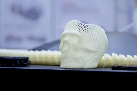 Small prototype human skull 3D printed molten white plastic on surface close-up Stock Photos