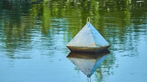 A small pyramidal white buoy floats on the surface of the water. Reflection i Stock Footage 158025250