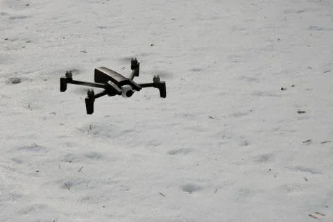 A small quadcopter flies on the background of snow. Stock Photos