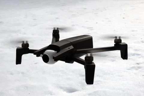 A small quadcopter flies on the background of snow. Stock Photos