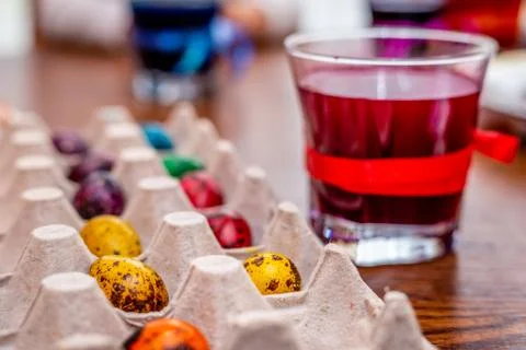 Small quail eggs painted for the easter holidays and a glass of paint. Foto stock
