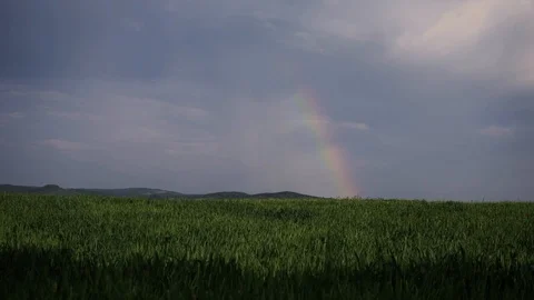 A small rainbow breaks out from under the black clouds Stock Footage 111748828