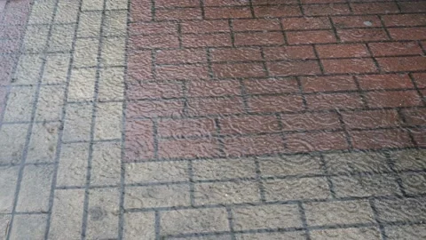 Small raindrops fall in a puddle on the city's tile sidewalk on a gloomy day  스톡 동영상 124892186