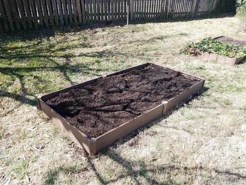 Small raised bed garden in backyard with soil Stock Photos