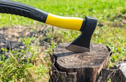 A small, rather heavy ax stuck in a stump for chopping wood. Close-up photogr Stock Photos