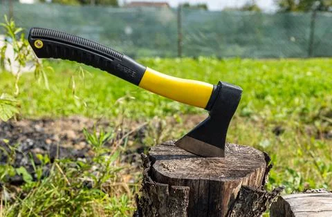 A small, rather heavy ax stuck in a stump for chopping wood. Close-up photogr Stock Photos