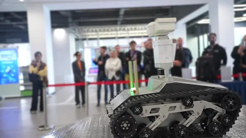 Small reconnaissance robot with caterpillar tracks performing a demonstration by Stock Footage 328988457
