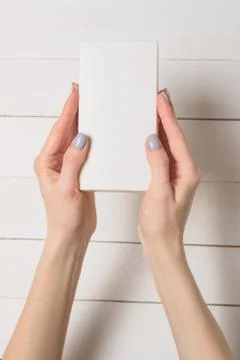 Small rectangular box in female hands. Top view. White table on the backgroun Stock Photos
