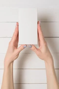 Small rectangular box in female hands. Top view. White table on the backgroun Foto stock