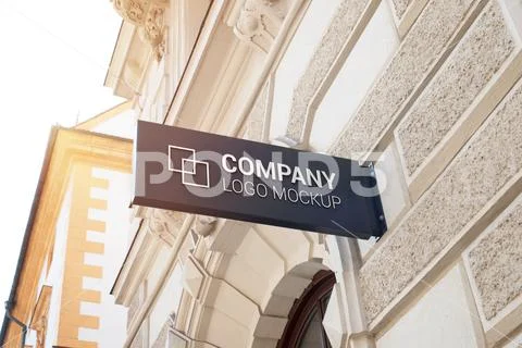 Small rectangular sign with company logo mockup on modern city center building w PSD Template