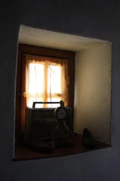 Small rectangular window with curtain and sun light, old clock and radio Stock Photos