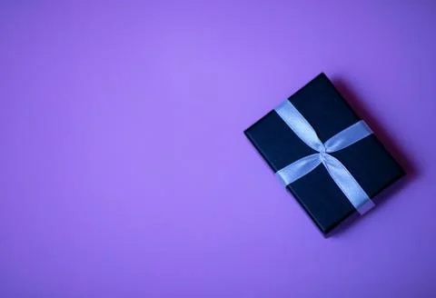 Small rectegular black gift box on colorful purple background Stock Photos
