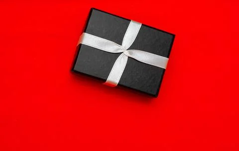 Small rectegular black gift box on a red background Stock Photos