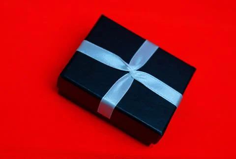 Small rectegular black gift box on a red background Stock Photos
