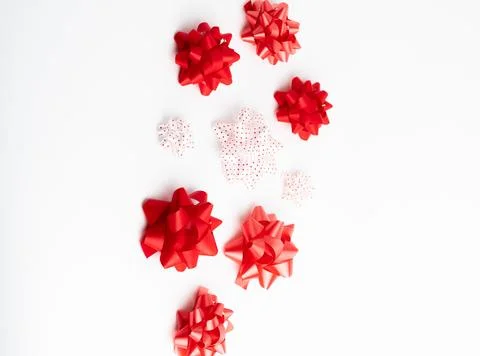 Small red and white decorative gift ribbon bows scattered on white background Stock Photos