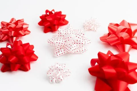 Small red and white decorative gift ribbon bows scattered on white background Stock Photos