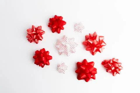 Small red and white decorative gift ribbon bows scattered on white background Stock Photos