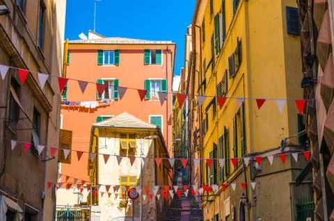 Small red and white flags hang above street with colorful multicolored buildi Stock Photos