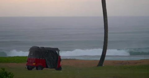 Small red auto rickshaw tuk tuk covered with gray cloth during heavy tropical Stock Footage 227951776