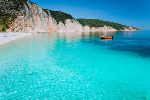 Small red boat on clear blue sea water near to amazing beach on mediterranean Stock Photos
