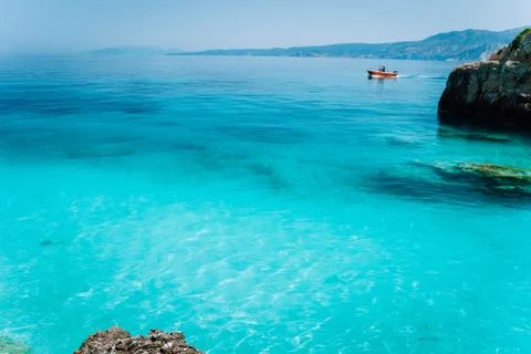 Small red boat floating on clear blue sea water. Summer beach vacation Stock Photos