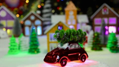 A small red car moves against the backdrop of a large Christmas town Stock Footage 292768003