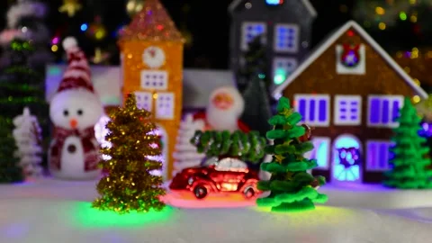 A small red car moves through a Christmas town with houses and Christmas trees Stock Footage 295478813
