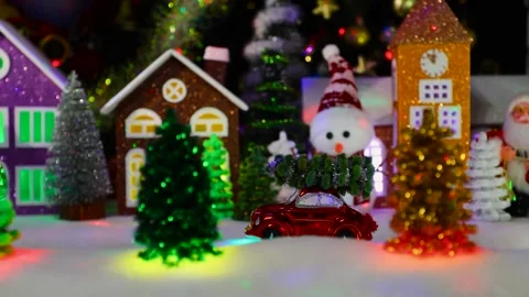 A small red car moves through a Christmas town with houses and Christmas trees Stock Footage 295479151