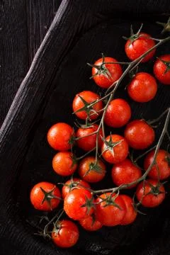 Small red cherry tomatoes on an old dark wooden table in rustic style Stock Photos