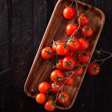 Small red cherry tomatoes on an old dark wooden table in rustic style Stock Photos